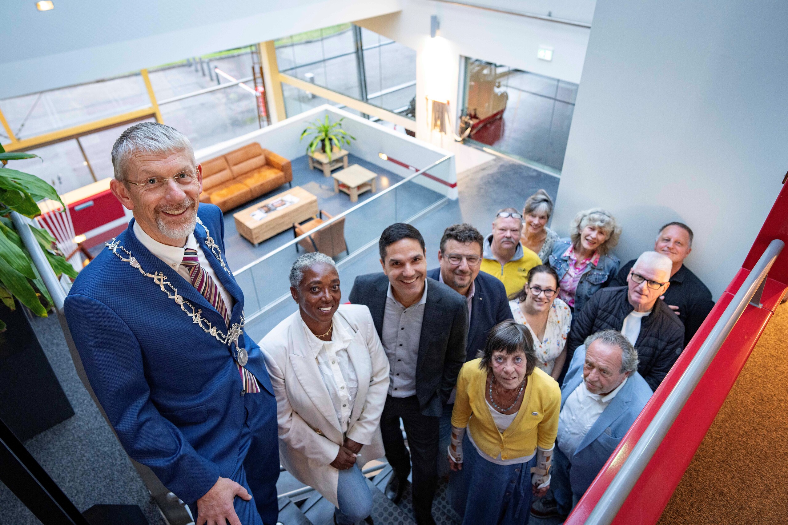 Burgemeester de Boer met vertegenwoordigers van deelnemende organisaties en buurtbemiddelaars op een trap