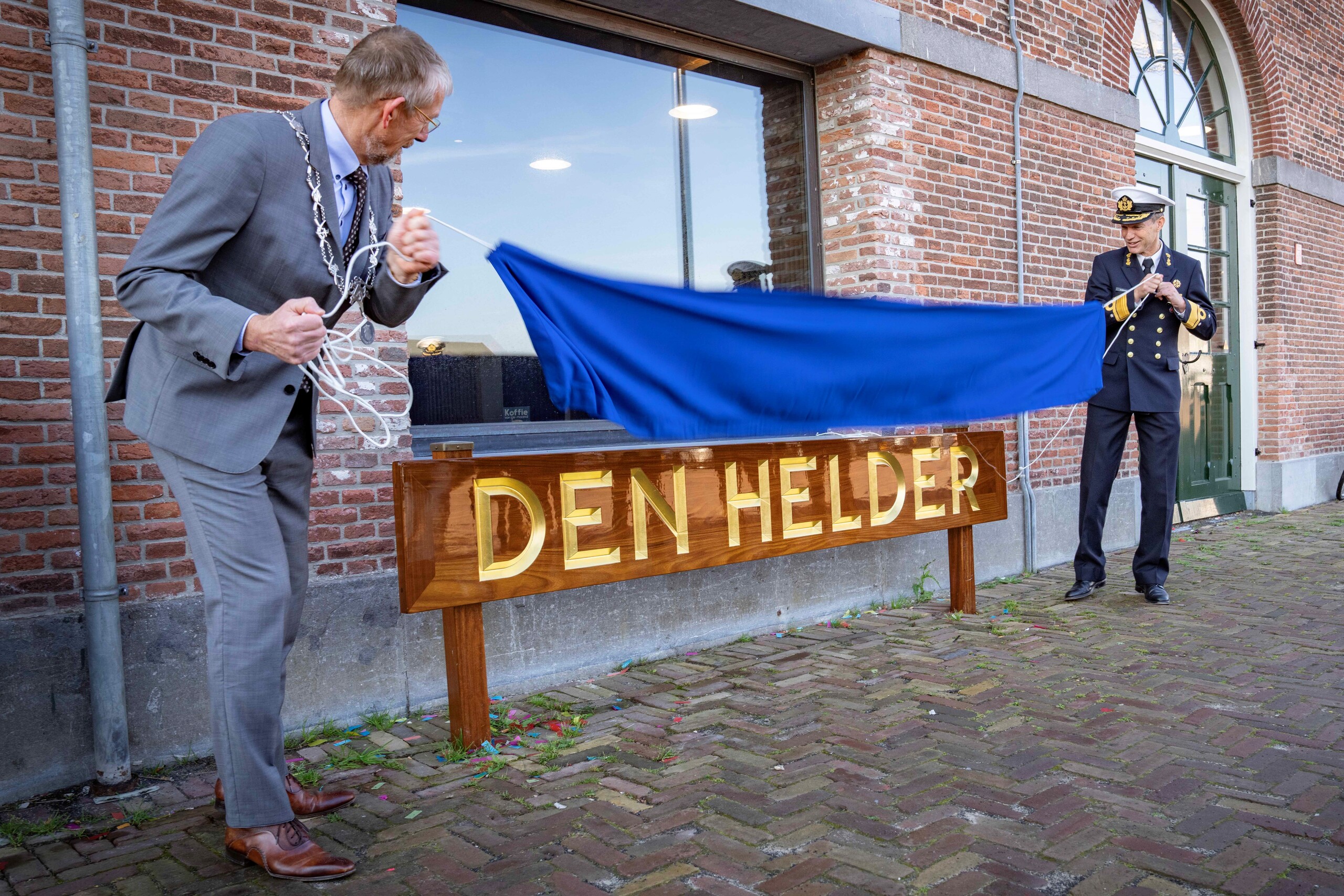 Jan de Boer en Harold Liebregs met naambord 'Den Helder' bij gebouw 66