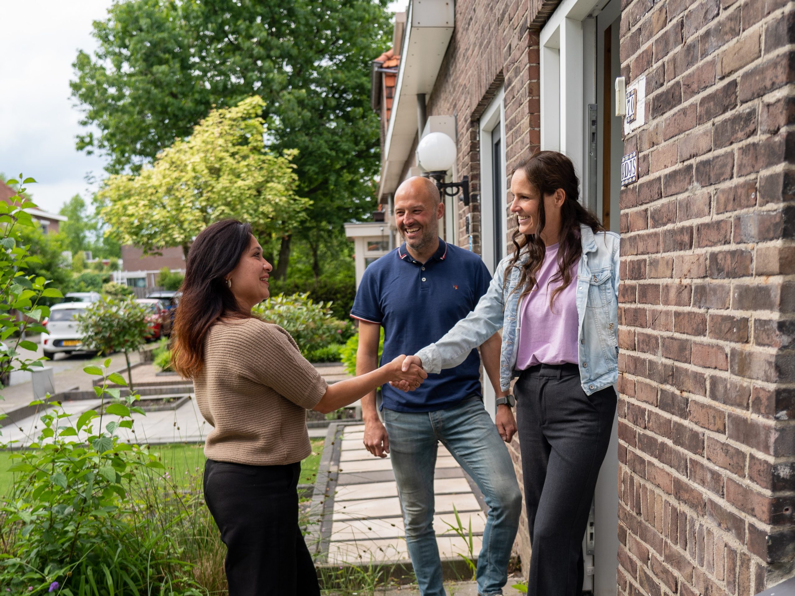 Personen schudden hand bij huis