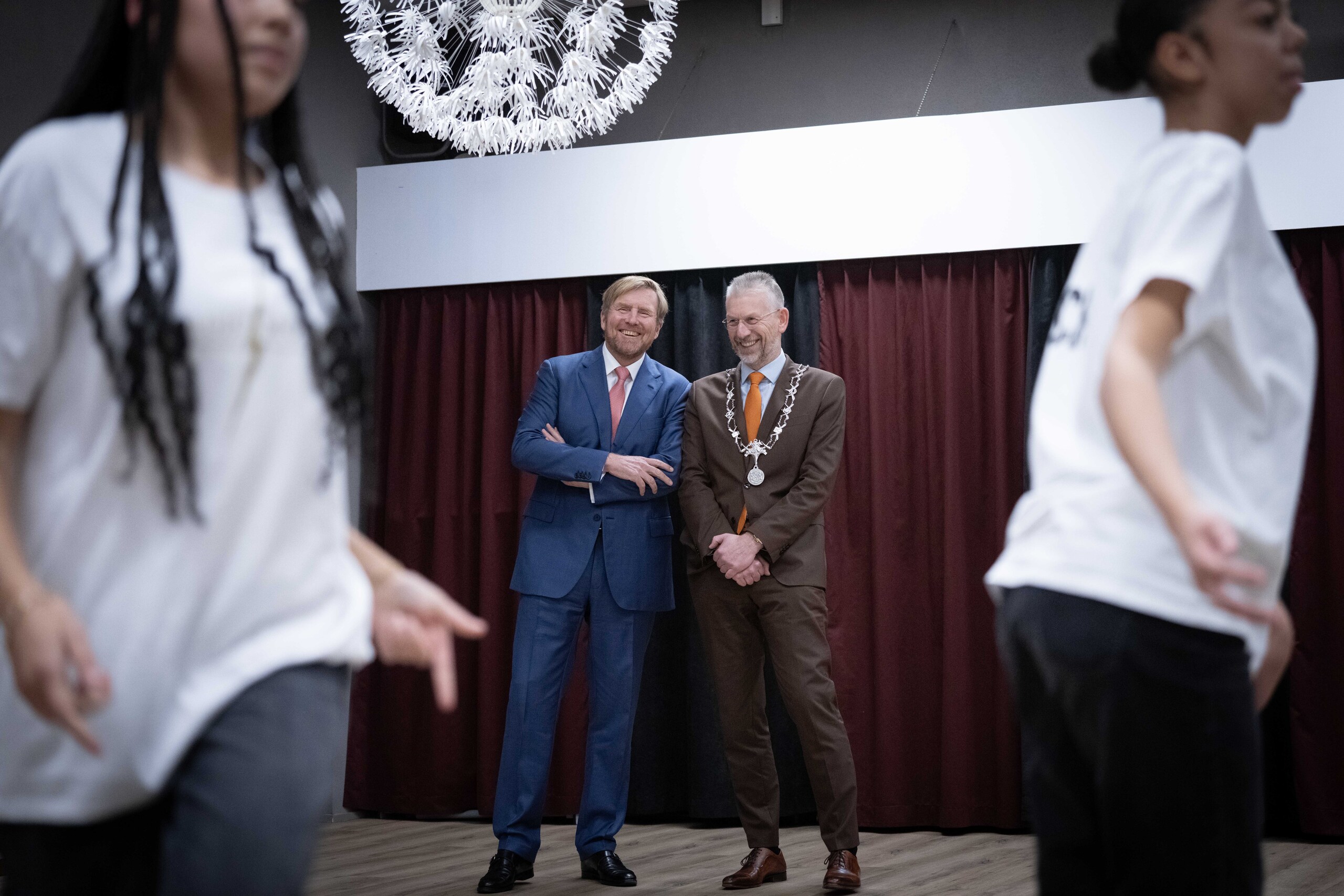 De Koning en burgemeester Jan de Boer amuseren zich bij een optreden van Magic Moves