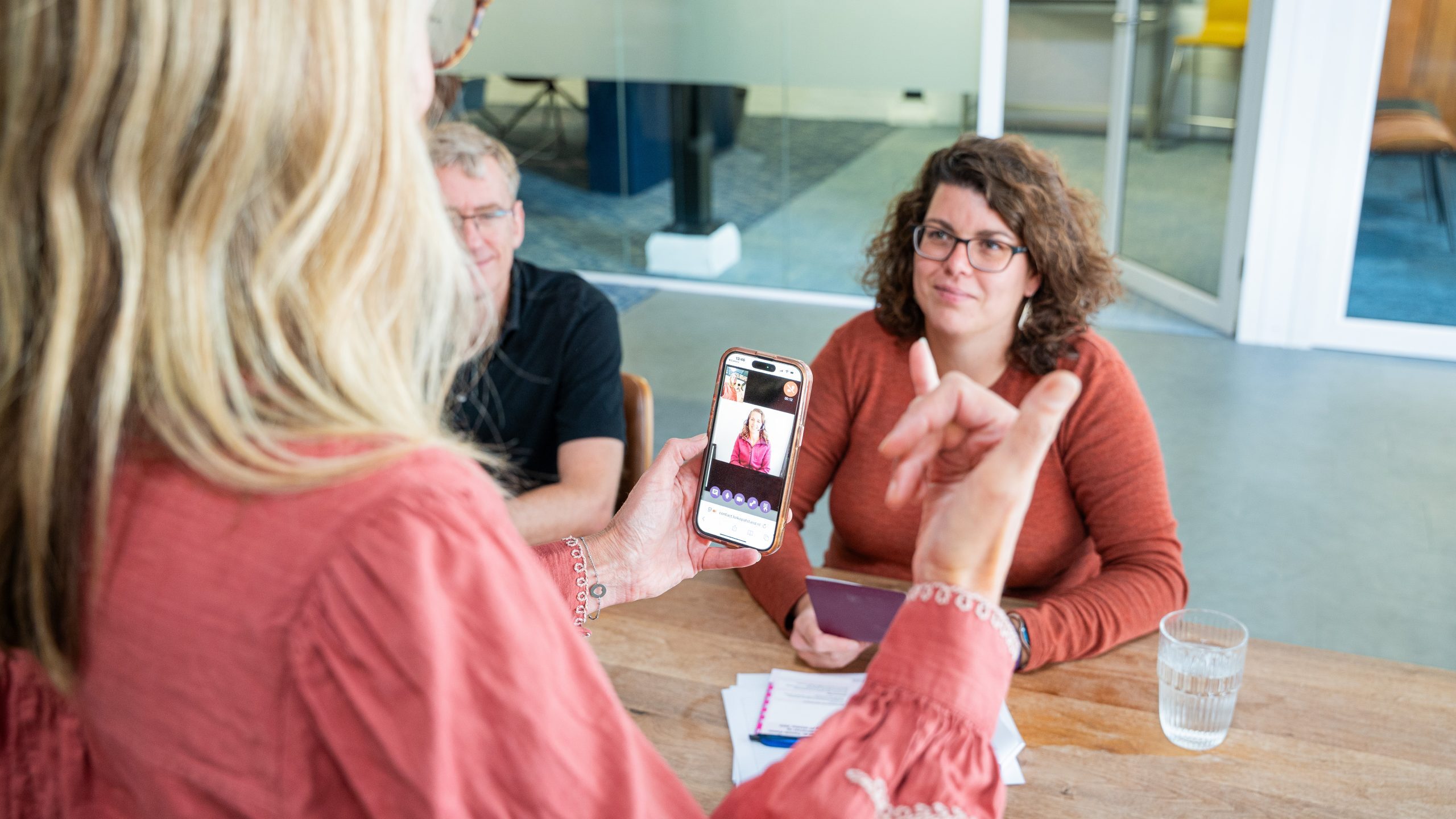 Een mevrouw gebruikt 'Tolk op afstand' op haar telefoon in het stembureau