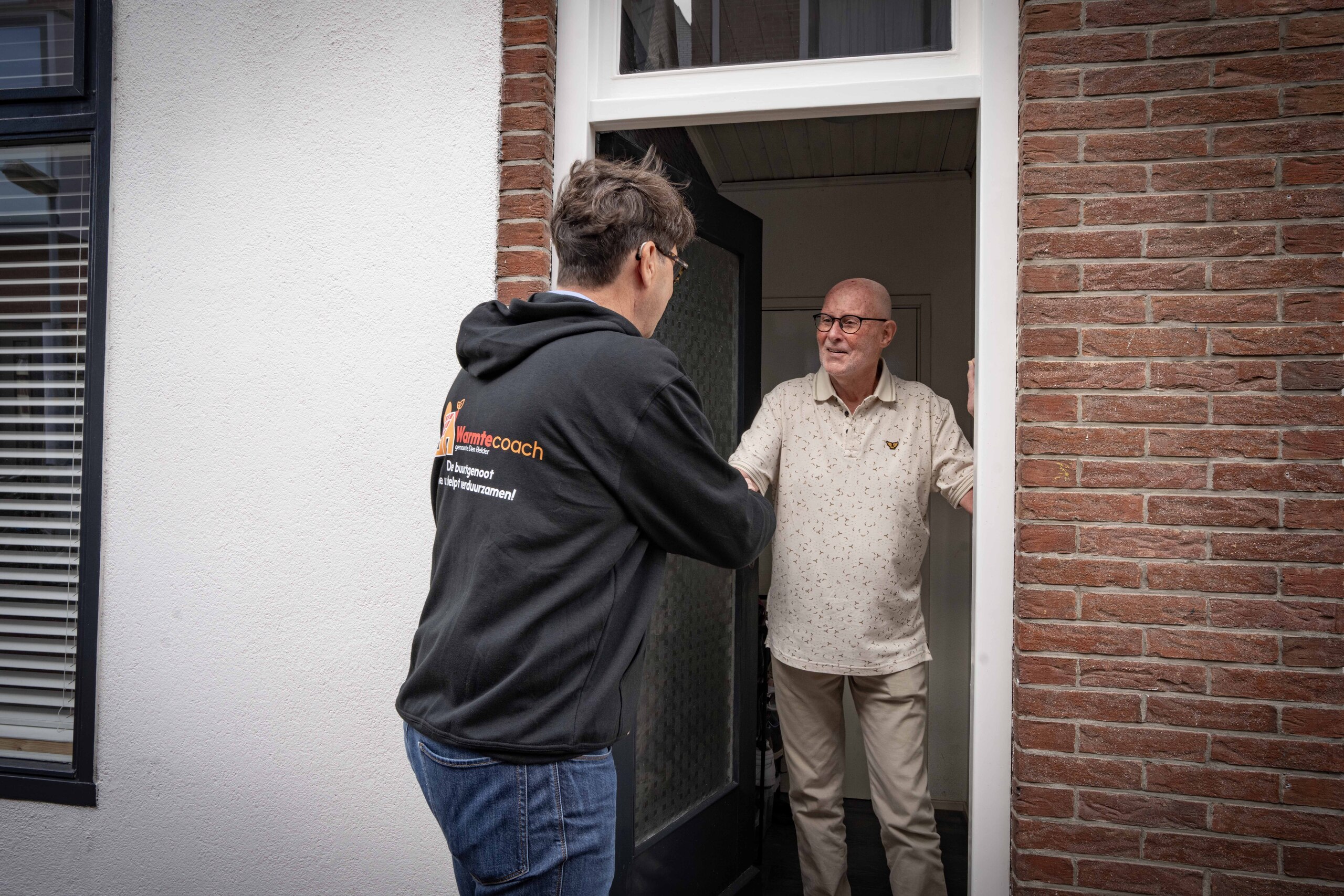 Mannen schudden elkaar de hand bij voordeur van woning